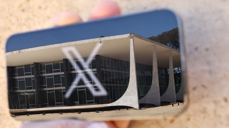 X's logo seen on a phone by a reflection of Brazil's Supreme Court. Pic: Reuters